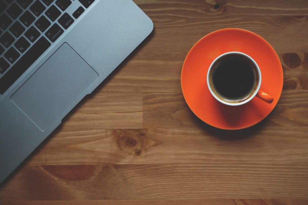 achats avec ordinateur, café et carnet sur un bureau